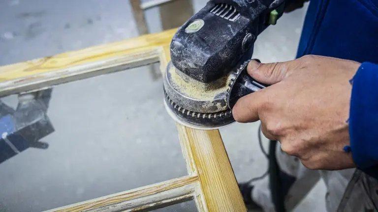 En fönsterbåge slipas med slipmaskin inför fortsatt renovering.