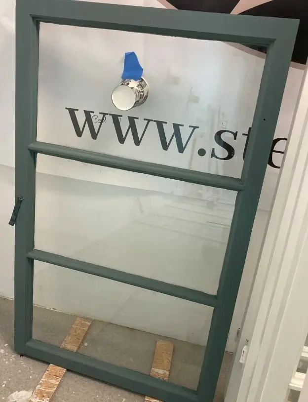 Grönmålad fönsterbåge med tre rutor efter renovering.